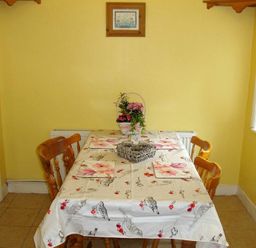 A dining area with a table covered by a patterned cloth and four wooden chairs at Briar Cottage in Town Yetholm and Kirk Yetholm