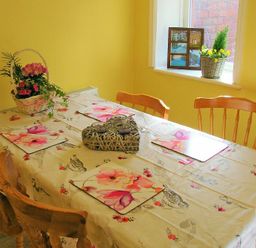 A dining area with a table covered in a floral tablecloth and wooden chairs at Briar Cottage in Town Yetholm and Kirk Yetholm
