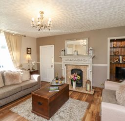 A living room with two sofas, a wooden coffee table, a fireplace with a mirror above, and a built-in shelf with decorations at Dray Cottage in Warkworth