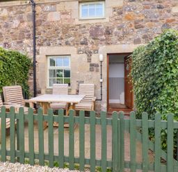 An outdoor seating area with a table and chairs at Heather Cottages - Brent Goose in Bamburgh