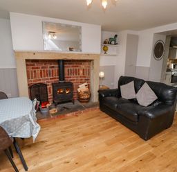 A living room with a fireplace and seating area at Heather Cottages - Brent Goose in Bamburgh