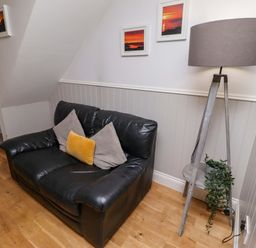 A living room with a sofa and lamp at Heather Cottages - Brent Goose in Bamburgh
