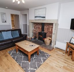 A living room with a fireplace and sofa at Heather Cottages - Godwit in Bamburgh