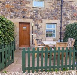 An outdoor patio area with a table and chairs at Heather Cottages - Grayling in Bamburgh