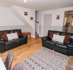 A living room with sofas and a table at Heather Cottages - Grayling in Bamburgh