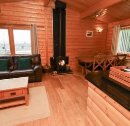 A living room with a sofa, coffee table, and fireplace at Heather Cottages - Grey Heron in Bamburgh