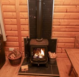 A living room with a wood stove and firewood at Heather Cottages - Grey Heron Bamburgh
