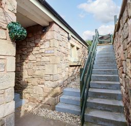 An outdoor area with stairs leading up to a building at Heather Cottages - Grey Seal Bamburgh