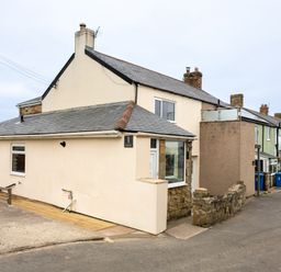 A row of houses on a street with a beige house at the corner marked number 1 at Island View in Amble