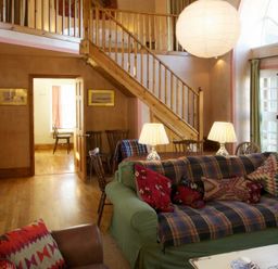 A living room with a wooden staircase two sofas and lamps by a window at Kirknowe in Jedburgh