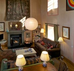 A living room with a fireplace brown sofa green curtains and lamps at Kirknowe in Jedburgh