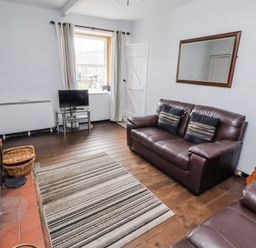 A living room with a sofa and television at Kittiwake Cottage, Budle Bay Bamburgh