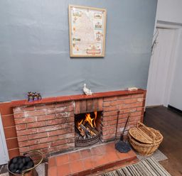 A living room with a fireplace and a map at Kittiwake Cottage, Budle Bay