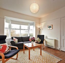 A living room with chairs sofa coffee table and a lamp at Melvin Cottage in Low Newton-By-The-Sea