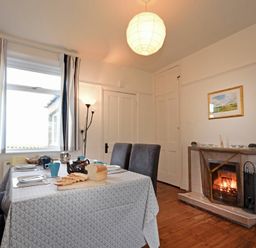 A dining room with a table set for a meal and a fireplace at Melvin Cottage in Low Newton-By-The-Sea
