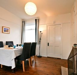 A dining room with a table covered with a cloth set for tea four chairs wooden floor and a fireplace at Melvin Cottage in Low Newton-By-The-Sea