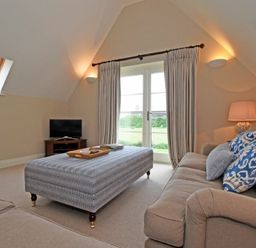 A living room with two sofas a large ottoman and a television at Sandpiper Bamburgh