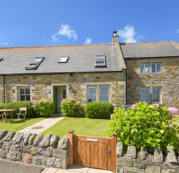 A stone cottage with skylights and a small garden with a wooden gate and outdoor table at Ottoline Cottage in Embleton