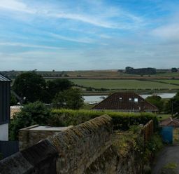 A view of a rural landscape with houses trees a river and fields at Pilots Rest in Alnmouth