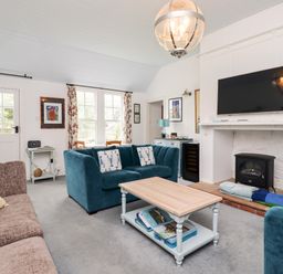 A living room with blue sofas a coffee table a wall mounted tv and a fireplace at Salty Dog in Bamburgh