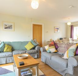 A living room with two sofas cushions a coffee table and a dining table with chairs at Schooner Court No1 in Alnmouth