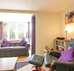 A living room with a sofa and armchair with purple cushions at Schooner Court No2 in Alnmouth
