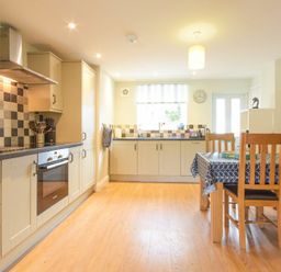 A kitchen with cabinets an oven a dining table with chairs and a window at Schooner Court No2 in Alnmouth