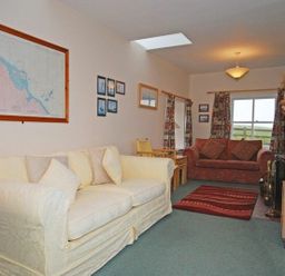 A living room with two sofas a red rug a wood stove and a television at Snook Point Cottage in Newton-by-the-Sea