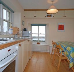 A kitchen with a stove sink countertop microwave and table with chairs at Snook Point Cottage Newton-by-the-Sea