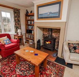 A living room with a stove and bookshelf at St Marys Cottages No4 Low Newton-by-the-Sea