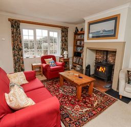 A living room with a sofa, armchair, coffee table and fireplace at St Marys Cottages No4 in Low Newton-by-the-Sea
