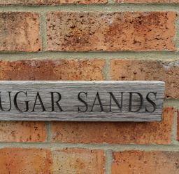 A sign reading SUGAR SANDS mounted on a brick wall at Sugar Sands in Longhoughton