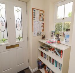 A hallway with a door and bookshelf at Sugar Sands in Longhoughton