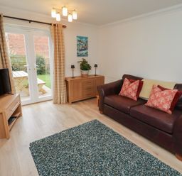 A living room with a sofa and television at Sugar Sands in Longhoughton