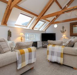 A living room with two sofas facing a television and wooden beams on the ceiling at The Boathouse (Seahouses) in Seahouses