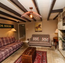 A living room with two sofas wooden chest coffee table stone fireplace and framed horse pictures at The Book House in Warkworth