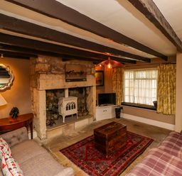 A living room with a fireplace two sofas a wooden chest and a patterned rug at The Book House in Warkworth