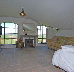 A living room with large windows a fireplace a sofa and a television at The Huffy House in Alnmouth