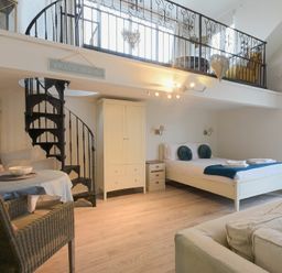 A bedroom with a bed bedside tables wardrobe and a spiral staircase leading to a loft at The Snug in Embleton