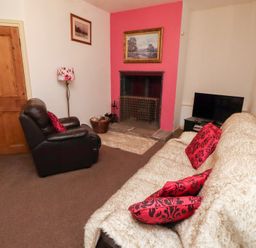A living room with a sofa and fireplace at Wayside Cottage in Newton-by-the-Sea