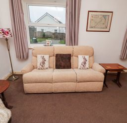 A living room with a sofa and a lamp at Wayside Cottage in Newton-by-the-Sea