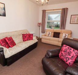 A living room with sofas and a lamp at Wayside Cottage in Newton-by-the-Sea