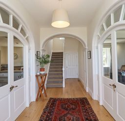 A hallway with wooden floor a rug and stairs at The Lookout Embleton