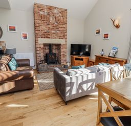 A living room with a fireplace and television at Red Fox in Lucker