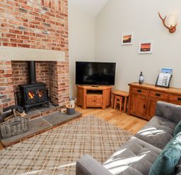 A living room with a fireplace and television at Red Fox in Lucker