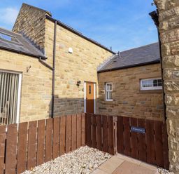 An outdoor area with a stone wall, fence, and a door at Roe Deer in Lucker