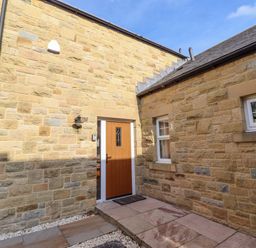 An entryway with a front door and stone walls at Roe Deer in Lucker