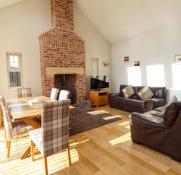 A living room with a fireplace and dining area at Roe Deer in Lucker