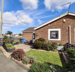 An outdoor area with flower beds and a house at Flora Cottage Beadnell