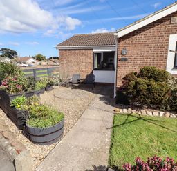 A garden with flower beds and seating at Flora Cottage Beadnell